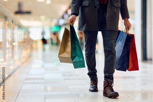 Unrecognizable man with shopping bags walking through mall.