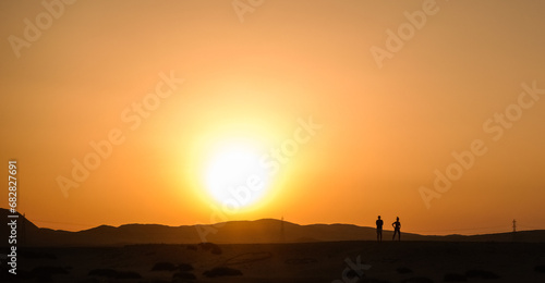 warm sundown without clouds bright sun and a photographer with a woman