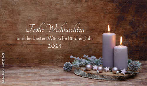 Weihnachtskarte: Romantische Weihnachtsdekoration mit zwei rosa brennende Kerzen, Tannenzweigen, Weihnachtskugeln und dem Text Frohe Weihnachten und die besten Wünsche für das Jahr 2024. photo