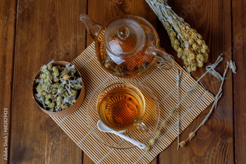 Natural Herbal Tea With Sideritis Scardica In Glass with teapot On Bamboo Mat, Wooden Background. Flat lay. photo