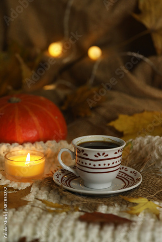 cup of coffee on the autumn background with leaves and candles