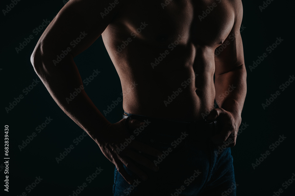 Silhouette photo of strong man showing his abs in studio. Partial shot