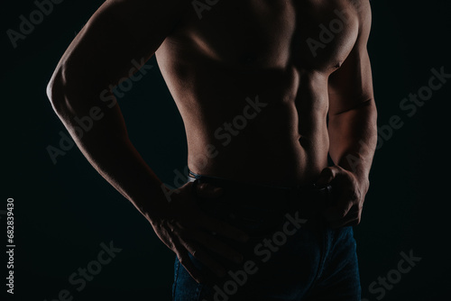 Silhouette photo of strong man showing his abs in studio. Partial shot © qunica.com