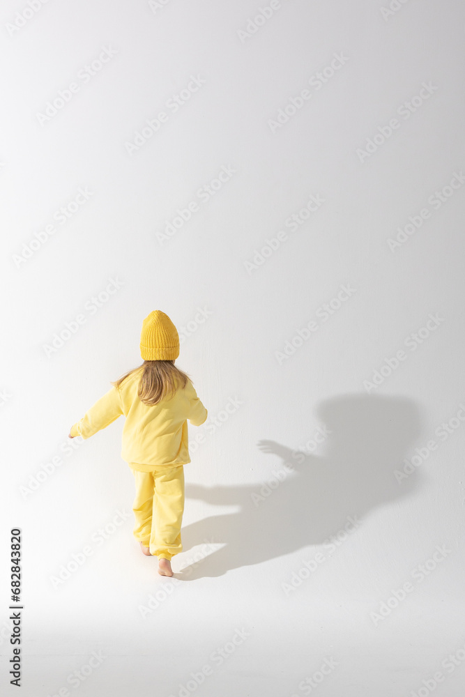 Portrait of beautiful cute little toddler girl. Child with funny face in yellow sweatshirt and hat. Pretty smile kid in studio on white background. High quality photo Portrait of beautiful cute little toddler girl. Child with funny face in yellow sweatshirt and hat. Pretty smile kid in studio on white background. High quality photo