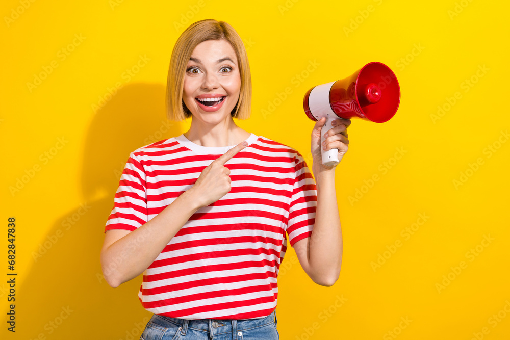 Portrait of impressed girl with bob hairdo wear stylish t-shirt directing at megaphone staring isolated on bright yellow background