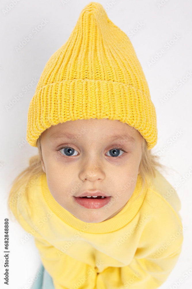 Portrait of beautiful cute little toddler girl. Child with funny face in yellow sweatshirt and yellow hat. Pretty smile kid in studio on white background. High quality photo Portrait of beautiful cute little toddler girl. Child with funny face in yellow sweatshirt and yellow hat. Pretty smile kid in studio on white background. High quality photo