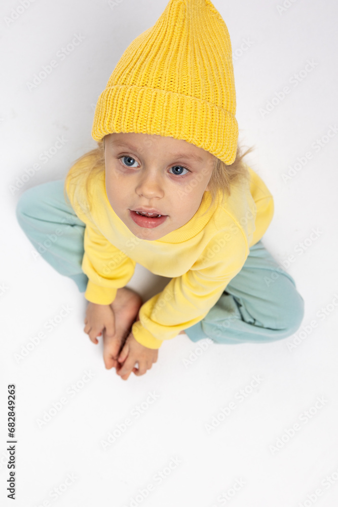 Portrait of beautiful cute little toddler girl. Child with funny face in yellow sweatshirt and yellow hat. Pretty smile kid in studio on white background. High quality photo Portrait of beautiful cute little toddler girl. Child with funny face in yellow sweatshirt and yellow hat. Pretty smile kid in studio on white background. High quality photo