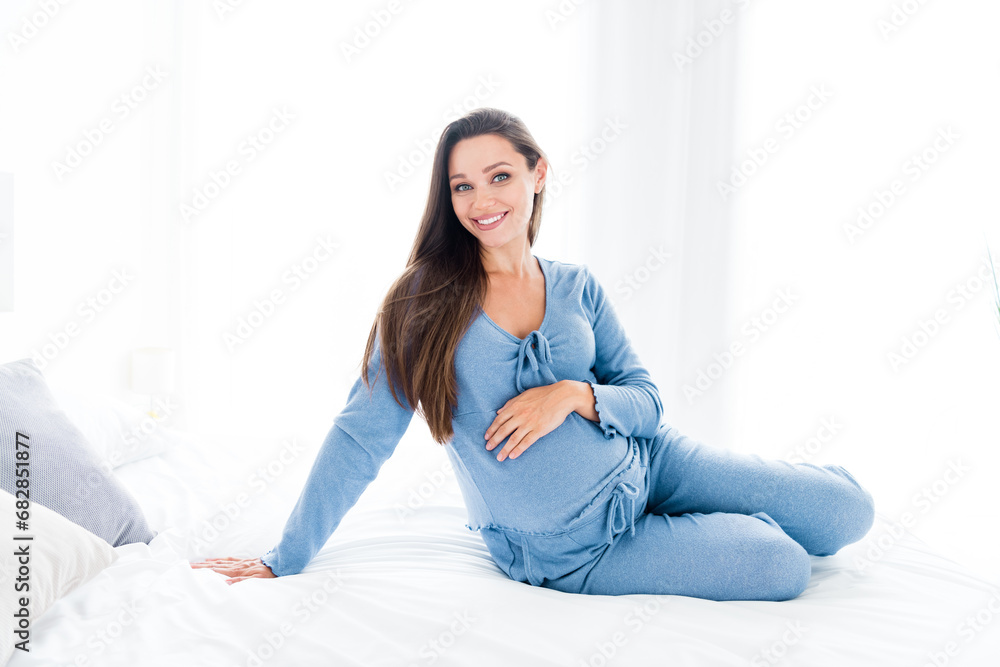 Photo of good mood cheerful young lady nightwear sitting cozy bed cuddling baby belly indoors house room Photo of good mood cheerful young lady nightwear sitting cozy bed cuddling baby belly indoors house room