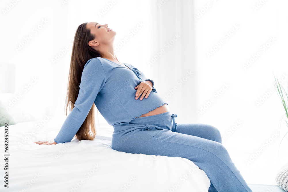 Profile side photo of lovely cute cheerful mommy sitting on comfortable sofa enjoying weekend holidays light room at home Profile side photo of lovely cute cheerful mommy sitting on comfortable sofa enjoying weekend holidays light room at home