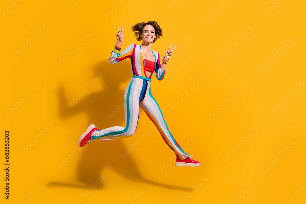 Photo of positive girl jumping make v sign celebrate festive holidays isolated shine color background