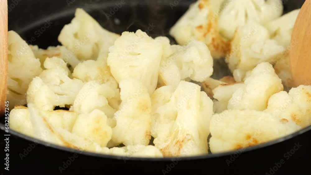 Fried cauliflower stirring with spoon in pan Fried cauliflower stirring with spoon in pan