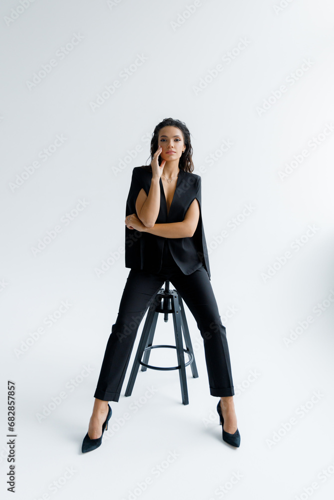 A luxurious sexy and beautiful girl at a photo shoot in a photo studio poses stylishly and fashionably in a black trouser suit A luxurious sexy and beautiful girl at a photo shoot in a photo studio poses stylishly and fashionably in a black trouser suit