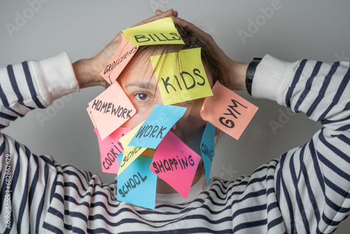 Mental load concept - female has post-it notes with social responcibilities on her face photo