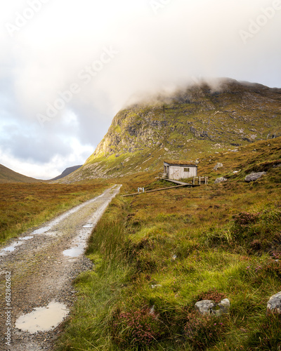 A bird hide along a farmer's track with a cloudy mountain in the background