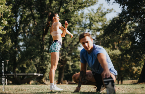 Motivated by their healthy lifestyle, a couple of professional athletes warm up outdoors. They exercise and practice in a park, surrounded by the natural environment.
