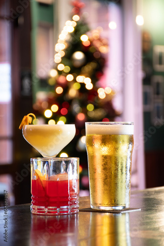 collection of alcoholic drinks with pint of lager beer and drinks and cocktails on a pub counter with a blurred Christmas tree in the background