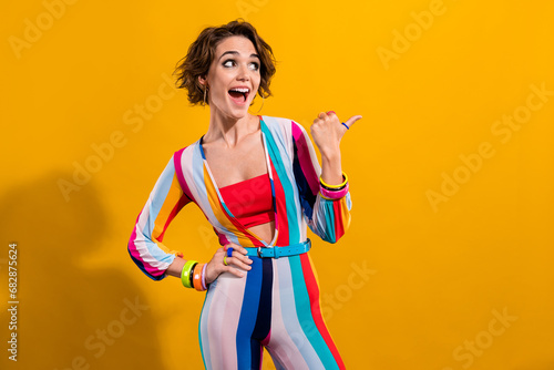 Photo of cheerful funky girl wear bright stylish outfit thumb demonstarte empty spcae isolated on vibrant yellow color background photo