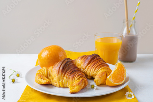 Freshly baked portuguese Brioche croissants on a plate with orange juice and chocolate milk. Tipical portuguese breackfast photo