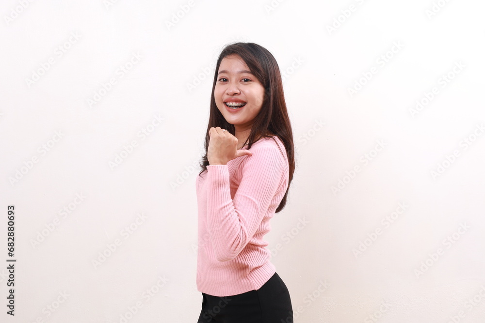 Happy cheerful young asian girl standing while pointing sideways. Advertisement and promotional concept. Isolated on white background Happy cheerful young asian girl standing while pointing sideways. Advertisement and promotional concept. Isolated on white background