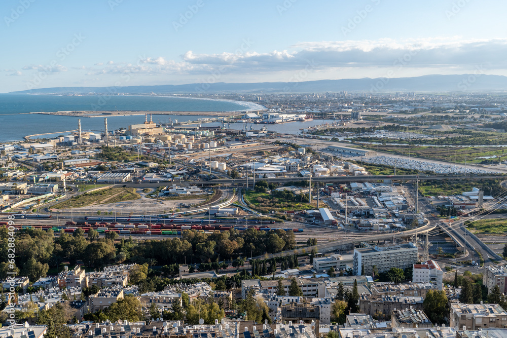 View of a shipping port, power station, railway and industrial facilities with a bay, residential neighborhoods and mountains in the background, HaKishon Port, HaKrayot, Haifa, Israel