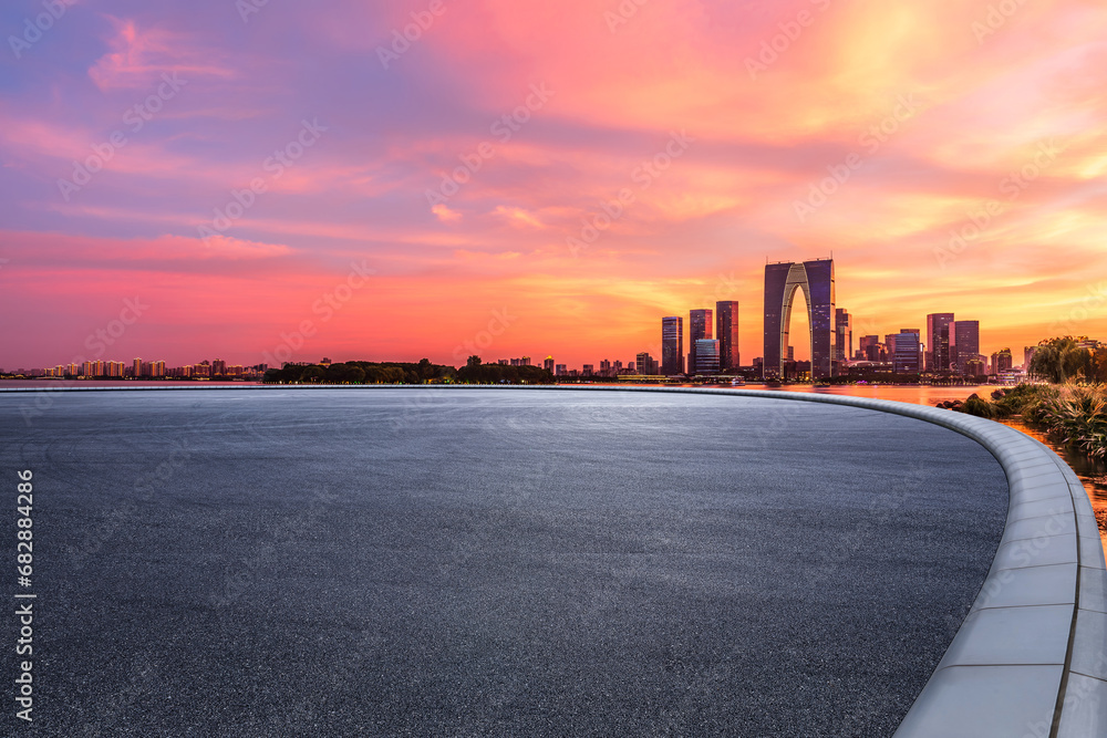 Asphalt road square and city skyline with modern buildings at sunset in Suzhou, Jiangsu Province, China.