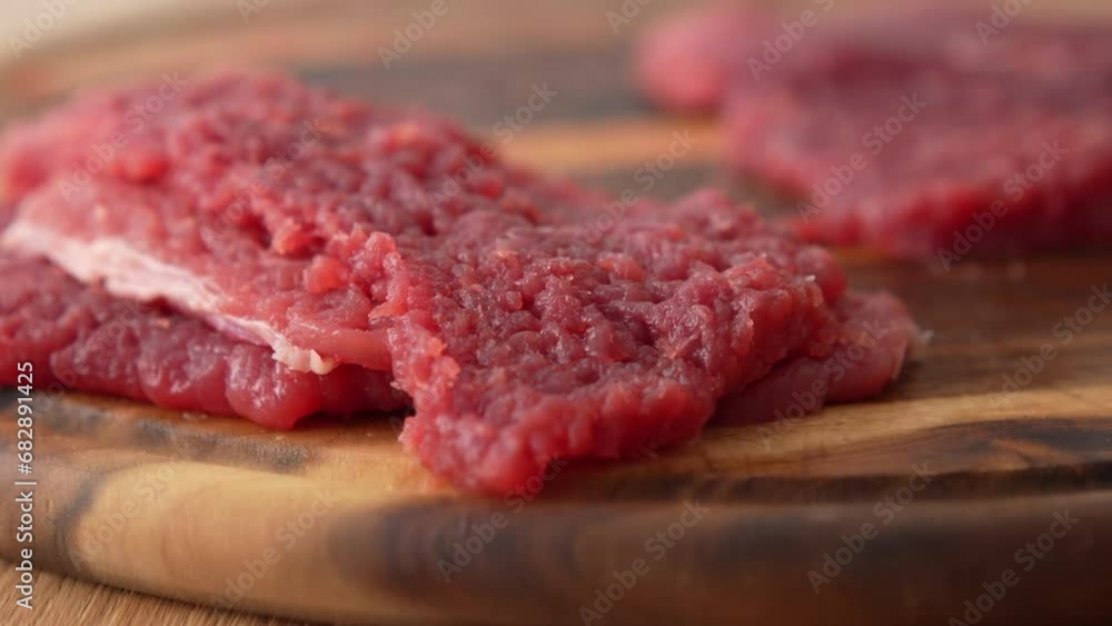 Panning shot of the process of beating raw meat on a wooden board. Panning shot of the process of beating raw meat on a wooden board.