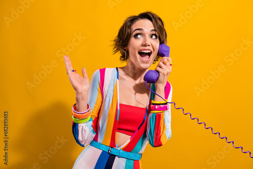 Photo of impressed funky lady wear striped costume talking phone looking empty space isolated yellow color background photo