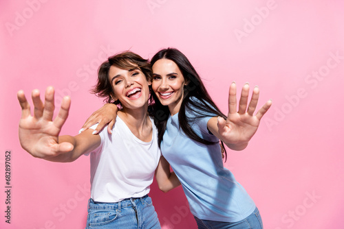Closeup portrait of two youngsters lovely family lesbians girls have fun waving palms you greetings isolated on pink color background photo