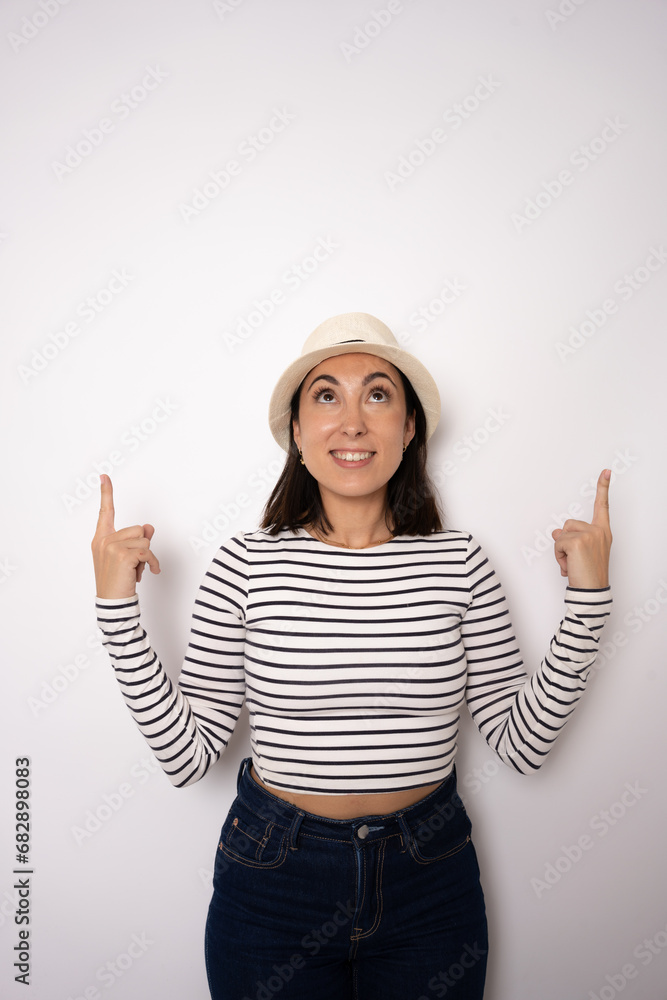 Young brunette woman wearing straw hat pointing fingers up isolated over white background. Young brunette woman wearing straw hat pointing fingers up isolated over white background.