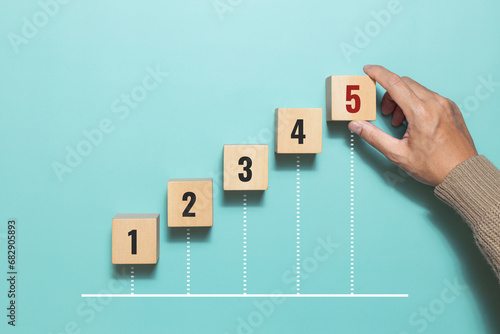 A man hand place wooden cubes with number five for rating. Priority of activities. Concept of task priority and management