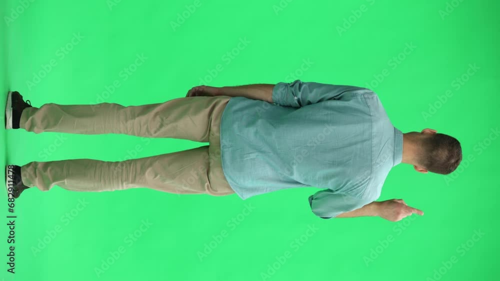 A young man on a green background in full growth tells an important, back view. A young man on a green background in full growth tells an important, back view.