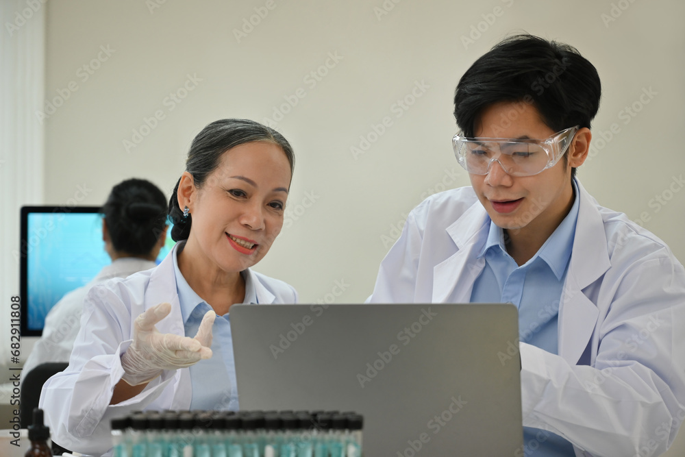 A senior science professor helps guide university student in conducting experiments and scientific research in the laboratory A senior science professor helps guide university student in conducting experiments and scientific research in the laboratory