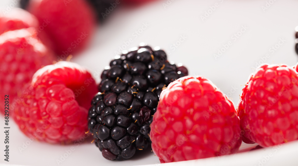 Raspberries and blackberries laid out on a white plate in circle Raspberries and blackberries laid out on a white plate in circle