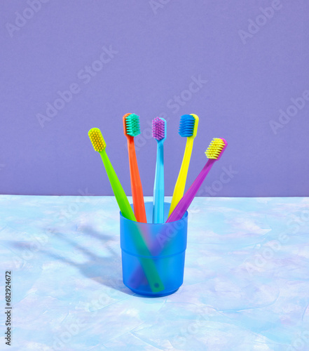 A composition of colored toothbrushes in a blue glass. Personal hygiene. Home dental care.