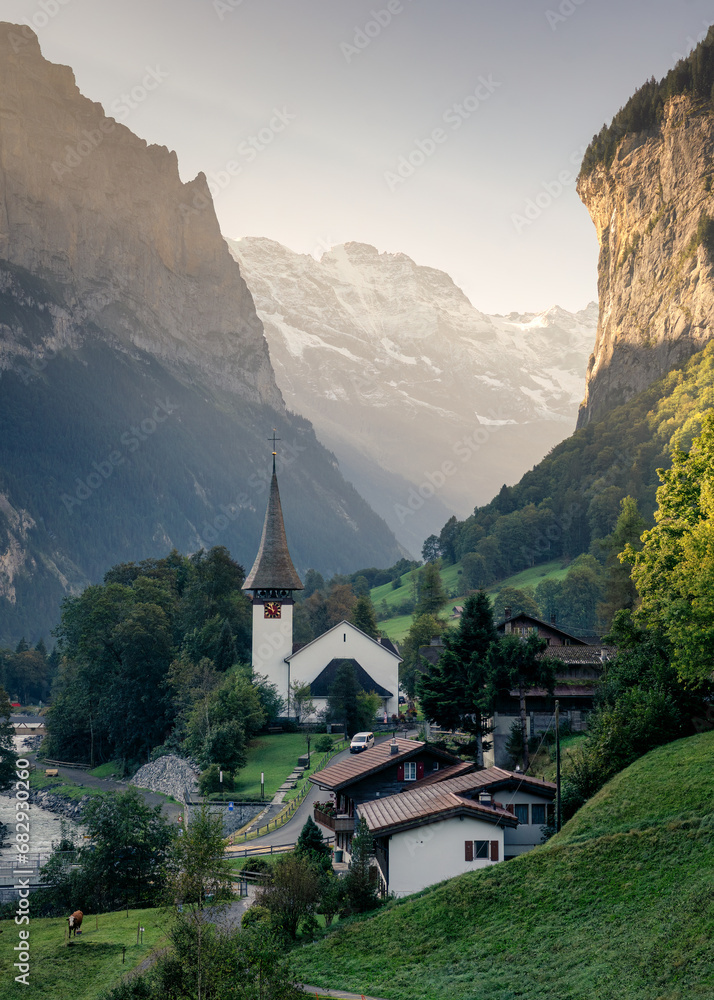 View of Lauterbrunnen valley with rustic village, famous church and Staubbach falls during end of summer at Switzerland