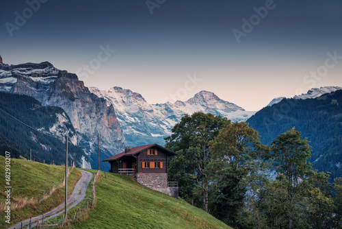 View from Wengen mountain village with Jungfrau and wooden cottage on hill in the evening at Switzerland