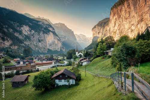 View of Lauterbrunnen valley with rustic village, famous church and Staubbach falls during end of summer at Switzerland photo