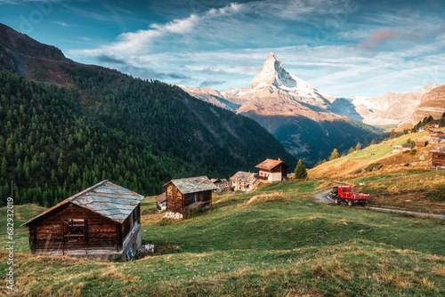 Matterhorn mountain with truck driving on the road and wooden huts on the hill in the morning on autumn at Zermatt, Switzerland