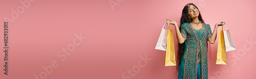 Obraz na płótnie cheerful indian woman in national costume posing with shopping bags and smiling