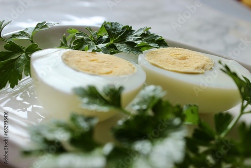 Boiled chicken egg and parsley on a white plate on a marble background