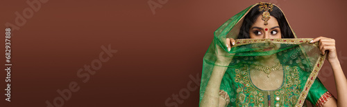 Obraz na płótnie pretty indian woman with bindi dot on forehead covering face with green veil loo