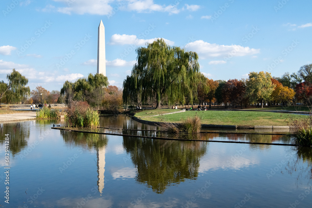 Washington monument and its reflection in a pond in the Constitution gardens in DC mall with blue skies and puffy clouds
