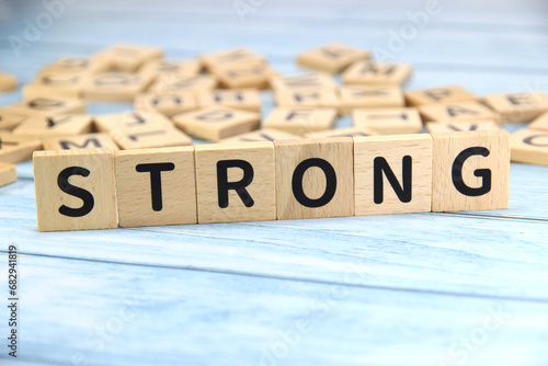 "STRONG" text or message short word english letter on wooden cubes block with blue vintage background.Copy space.