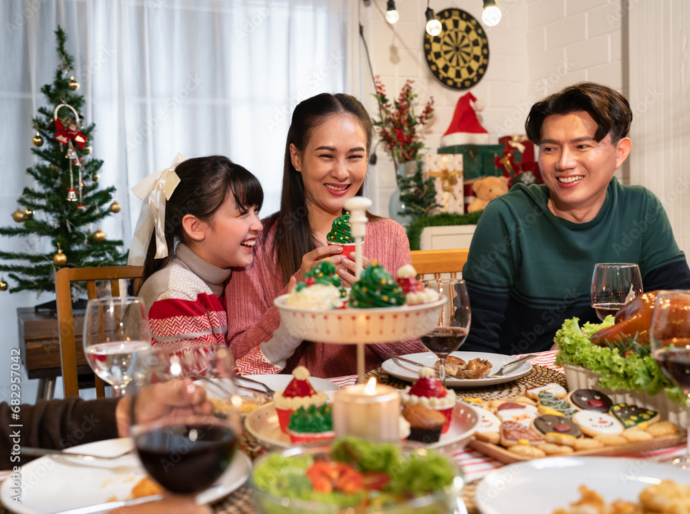 Naklejka premium Happy Asian family mother, father and daughter having dinner celebrating Christmas at home