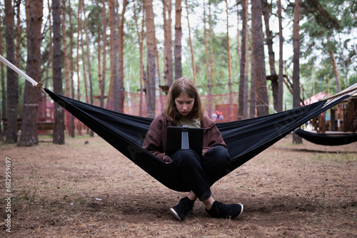 A girl in a hammock is working on a computer