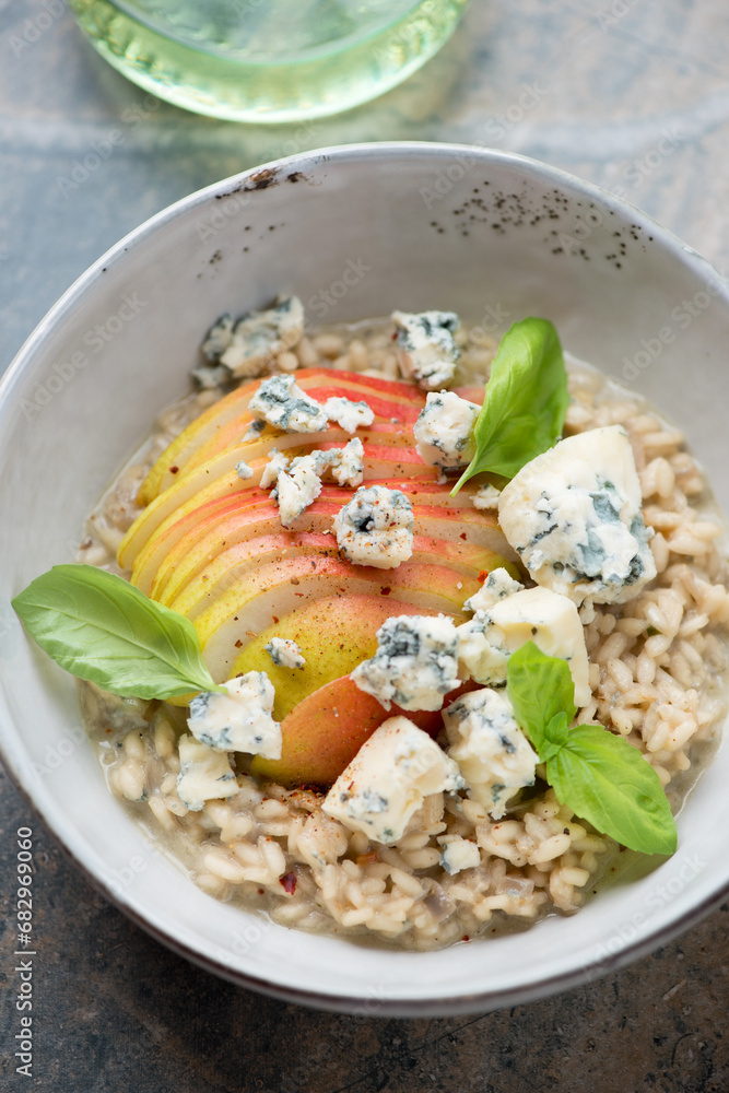 Risotto with pear, blue cheese and green basil leaves in a grey bowl, vertical shot, middle close-up Risotto with pear, blue cheese and green basil leaves in a grey bowl, vertical shot, middle close-up