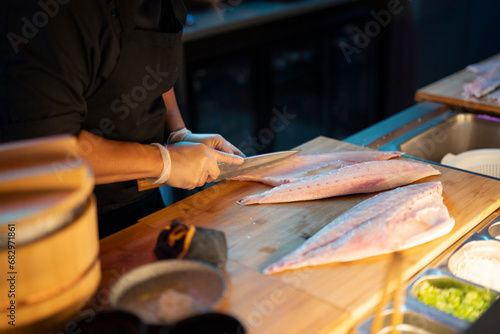 Chef preparing fish at a sushi restaurant counter photo