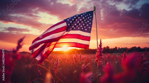The flag of the United States of America flutters in nature against the backdrop of the setting sun in pink rays.