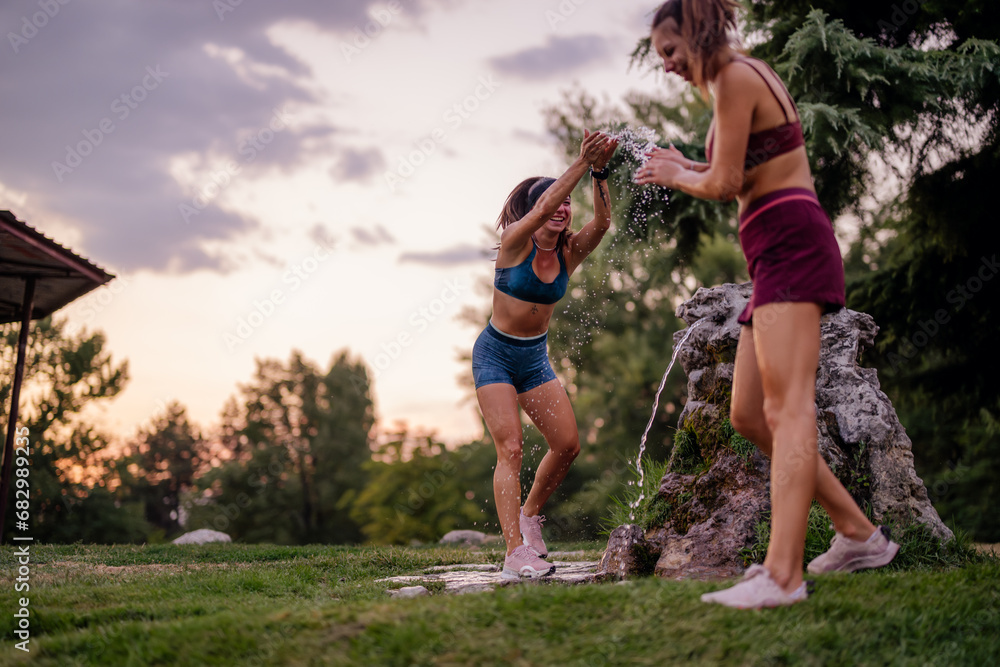 Fototapeta premium Happy Girls Having Fun Splashing Water in Green Park After Strenuous Training