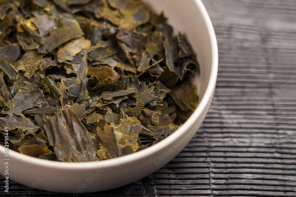 Raw dried Kombu seaweed in ceramic bowl. Asian dehydrated sea ingredient. Raw dried Kombu seaweed in ceramic bowl. Asian dehydrated sea ingredient.
